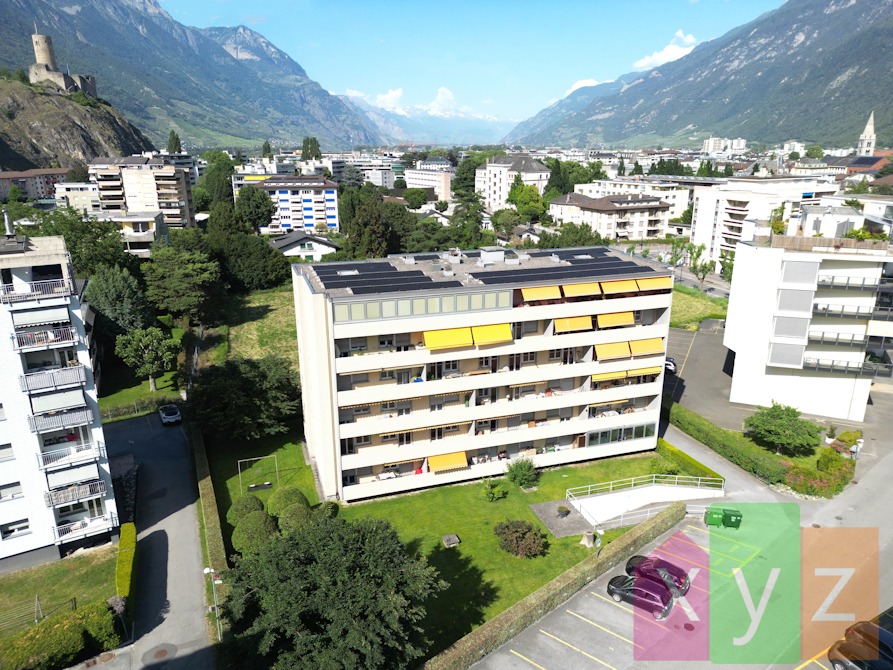 Vue aérienne de l'immeuble équipé de panneaux photovoltaïques et situé dans le quartier prisé de l'avenue de la Fusion à Martigny